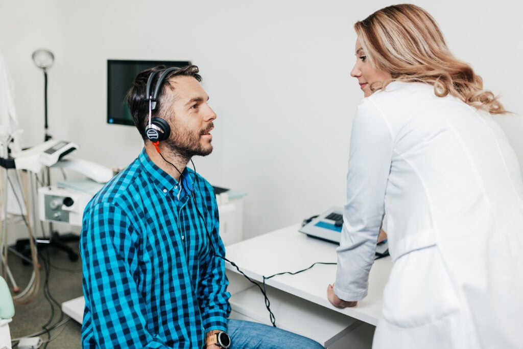 Мужчина на приеме у врача проходит проверку слуха